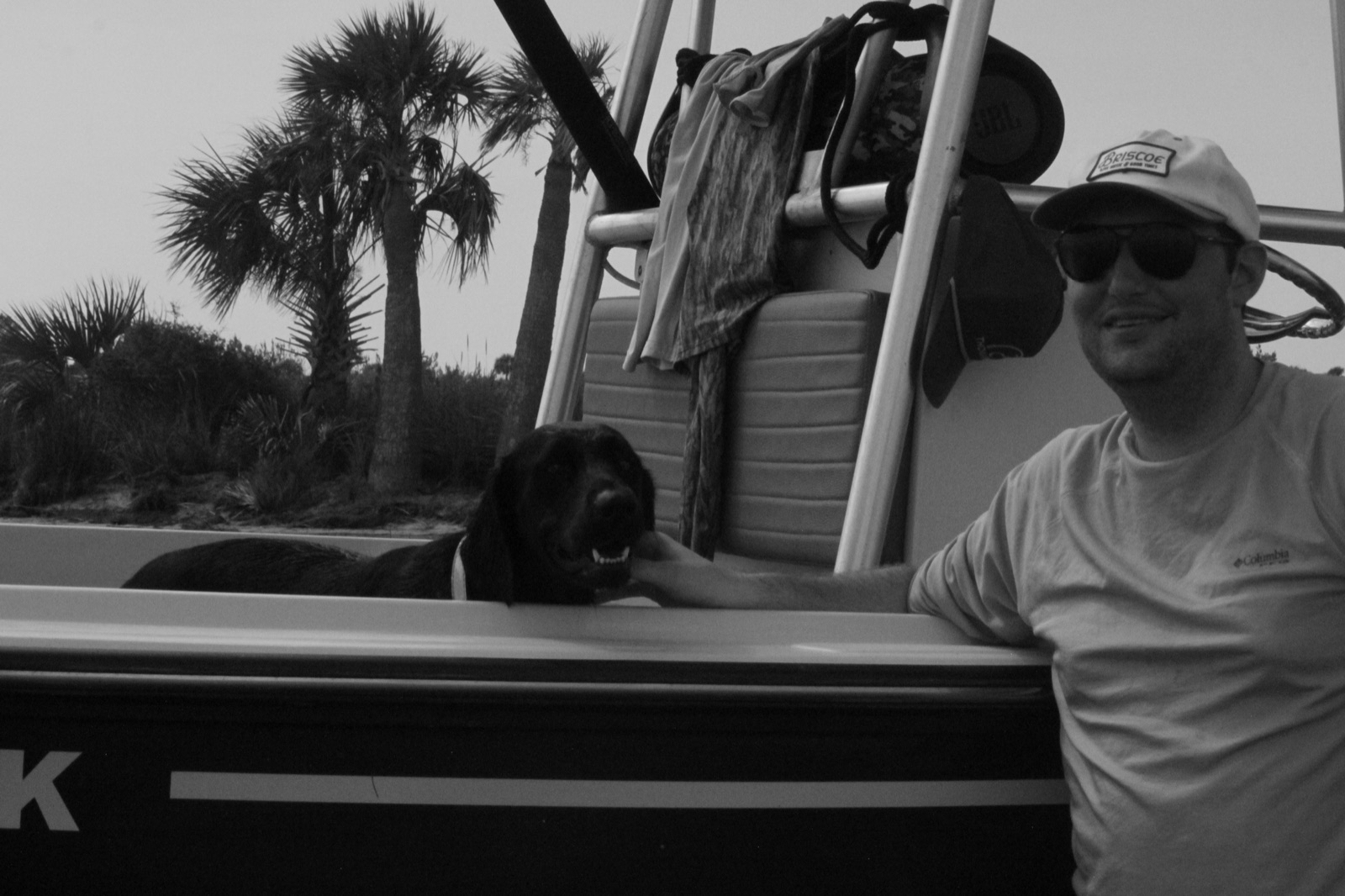 Angler and dog beside a skiff among the palms